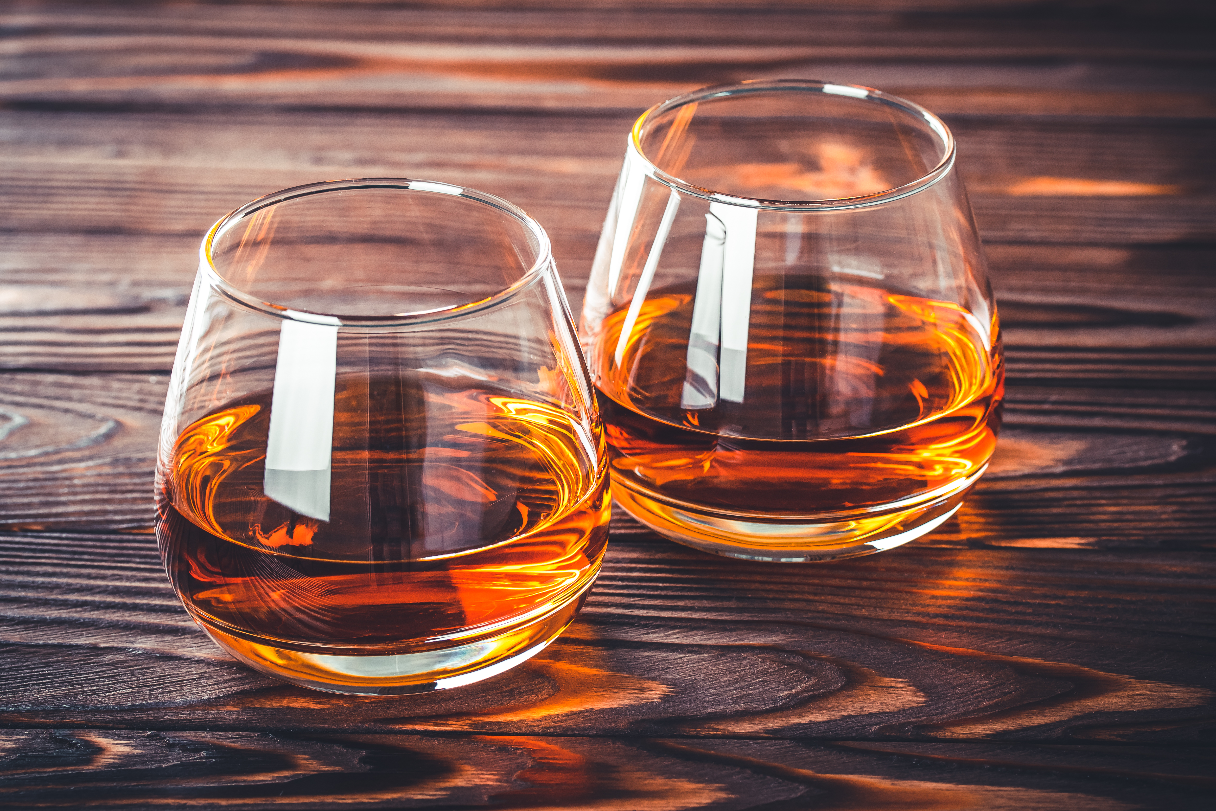Two glass of whiskey, cognac, brandy on a dark brown wooden table. Bourbon