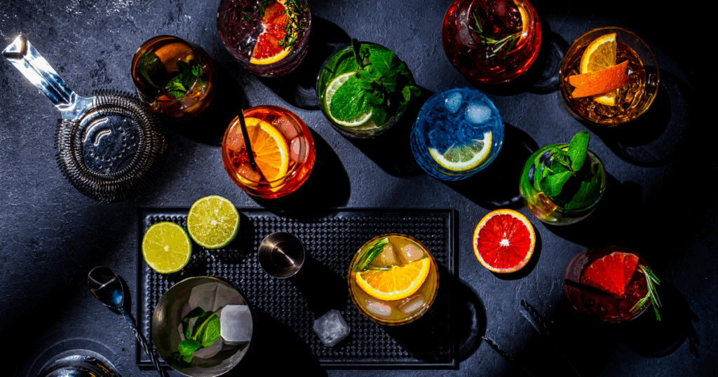 Colorful Home Bar Cocktails with Citrus Garnishes and Bartending Tools.