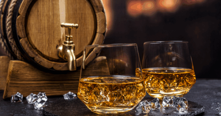 Two Glasses of Whiskey on Ice with a Wooden Barrel in the Background