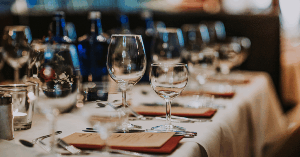 Formal event table setting with wine glasses and menus prepared for guests at a bulk liquor-supported party or corporate event.