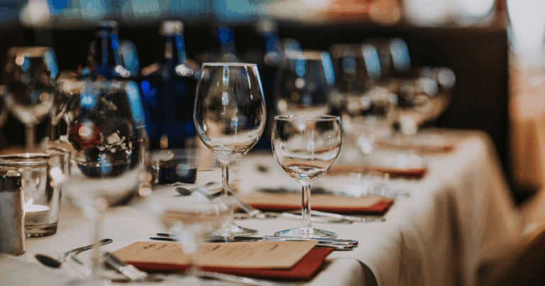 Formal event table setting with wine glasses and menus prepared for guests at a bulk liquor-supported party or corporate event.