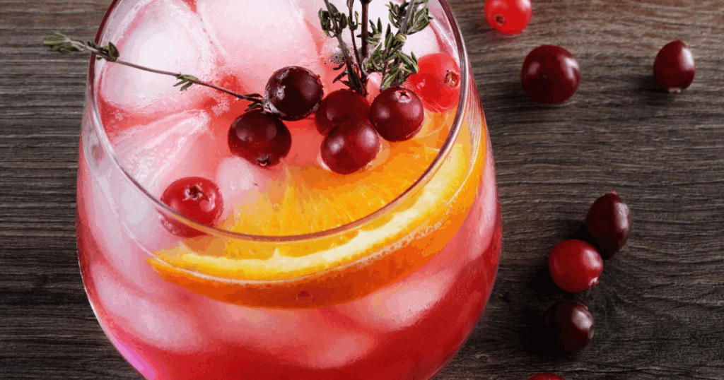 Festive cranberry holiday cocktail with orange slice and fresh garnish from Pina Wine & Spirits Kansas City