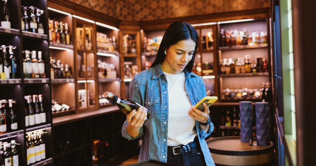 Woman shopping for wine at Pina Wine and Spirits in Kansas City while comparing bottles for holiday hosting.