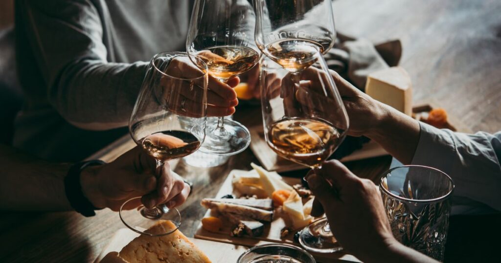Friends toasting glasses of white wine with a cheese board, showcasing seasonal wine tasting and Kansas City wine culture.
