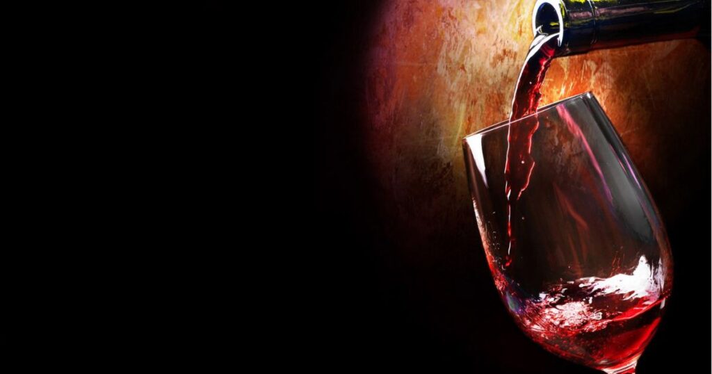 Red wine being poured into a glass against a warm background, symbolizing rich seasonal reds popular in Kansas City.