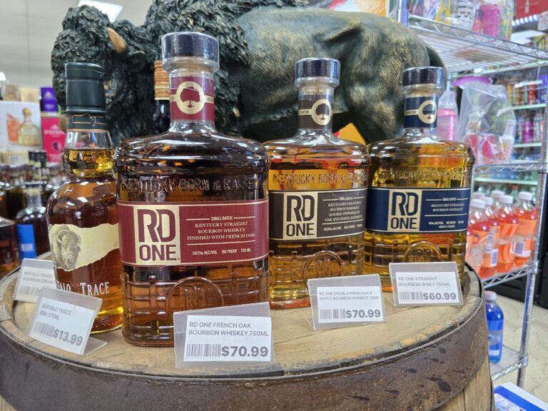 RD One Kentucky Straight Bourbon bottles displayed on a barrel at Pina Wine and Spirits with price tags, including French Oak finish and other limited bourbon options for Kansas City collectors and the bourbon secret.