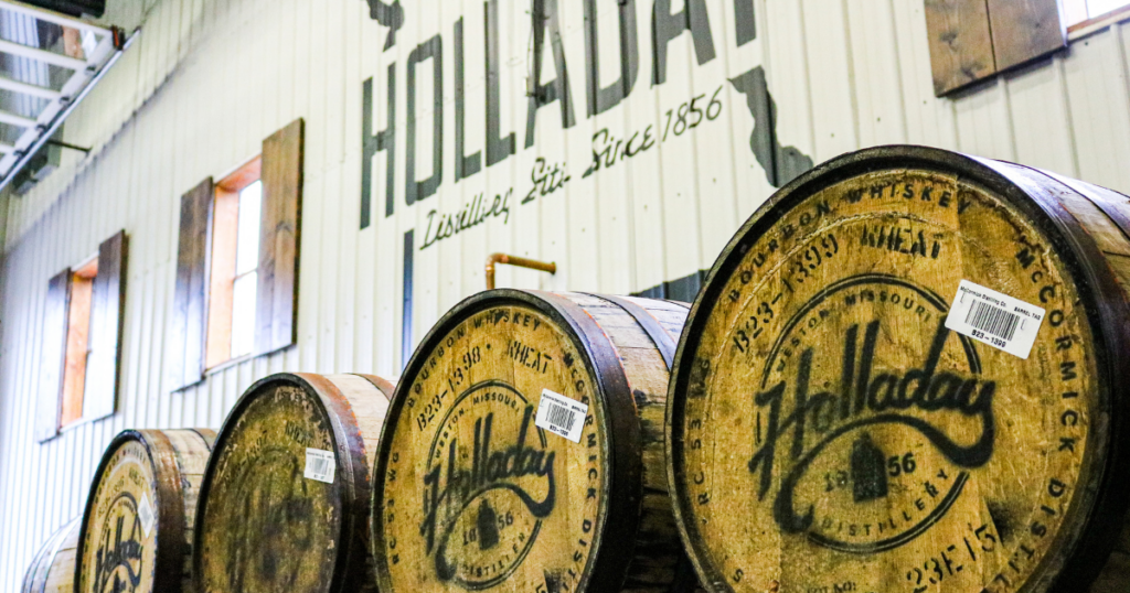 Top Missouri-Made Spirits You Should Be Drinking This Year 1 Sunlit wooden whiskey barrels marked Holladay at historic HOLLADAY Distillery—a proud tradition in quality spirits since 1856.